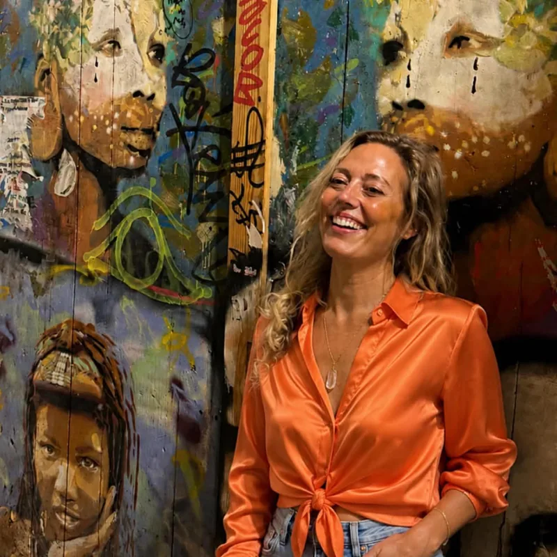Guest medium Cecilia Saber laughing in front of a painted mural
